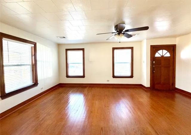a view of an empty room with window and wooden floor