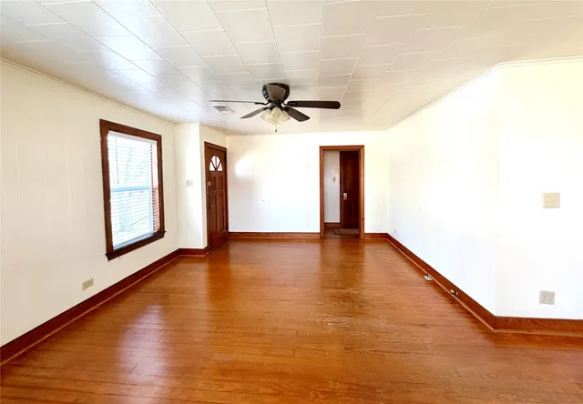 a view of empty room with wooden floor and fan