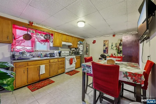 a kitchen with stainless steel appliances kitchen island granite countertop a dining table chairs and a refrigerator