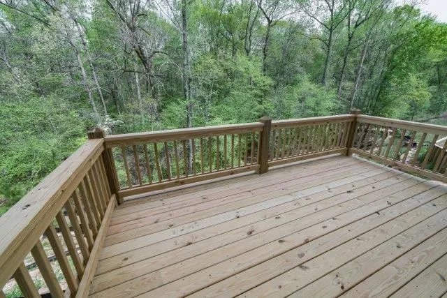 a balcony with wooden floor and trees in the back