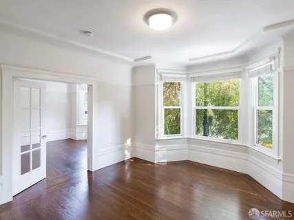 a view of an empty room with wooden floor and a window
