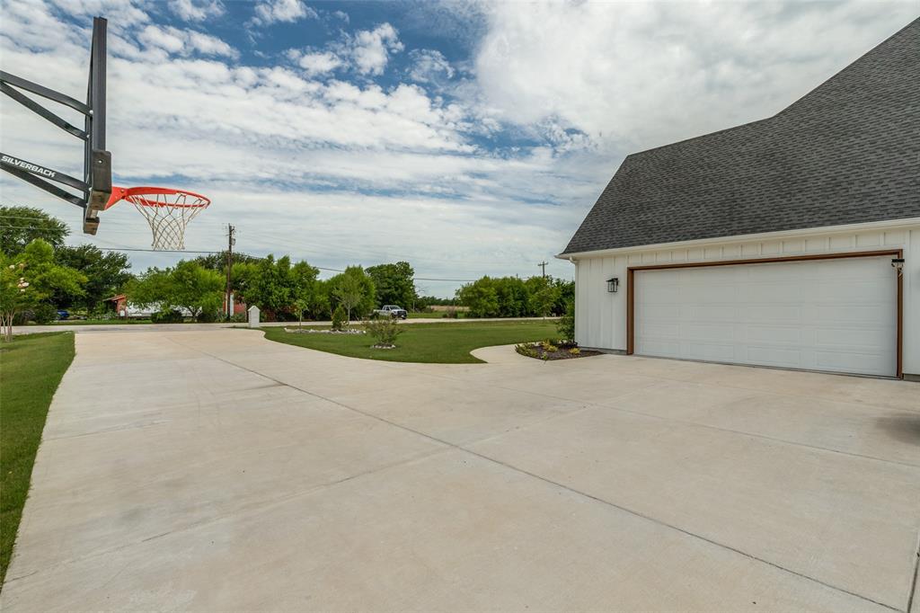 Huge concrete driveway with basketball hoop.