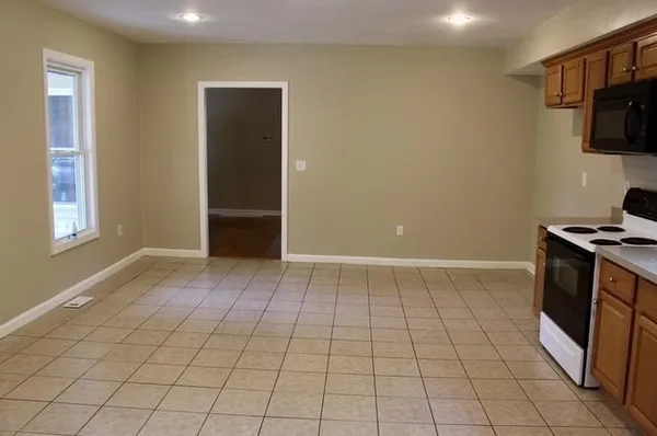 a view of an empty room with window and cabinet