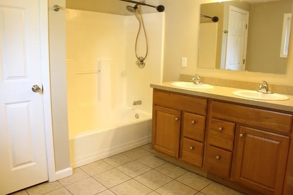 a spacious bathroom with a double vanity sink a mirror and a bathtub