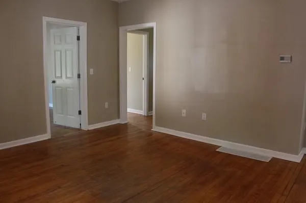 a view of an empty room with wooden floor and closet