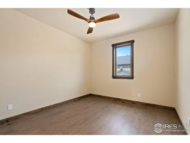 an empty room with wooden floor and ceiling fan
