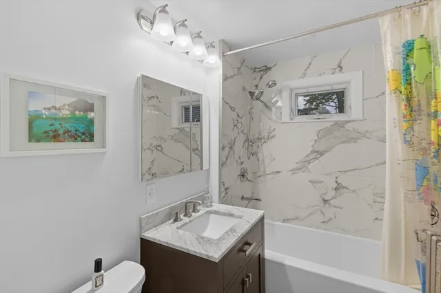 a bathroom with a granite countertop sink a toilet and shower