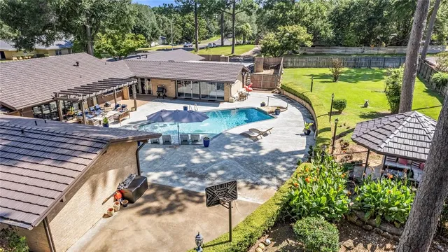 a view of a patio with table and chairs under an umbrella with large trees
