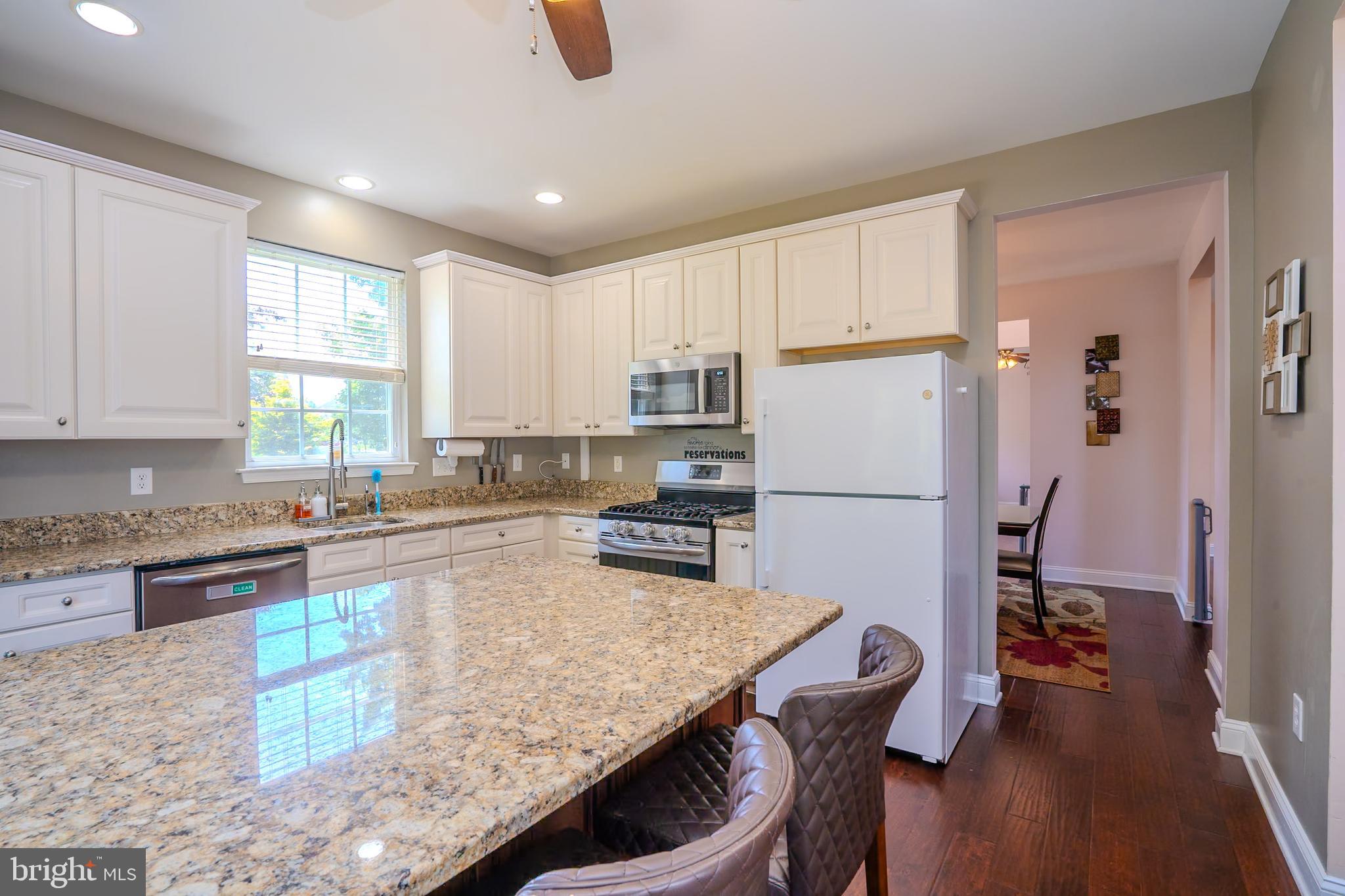 101 Beacon Drive Deptford, NJ 08096 - Photo 22 of 40 a kitchen with granite countertop a refrigerator a stove a sink a dining table and chairs with wooden floor