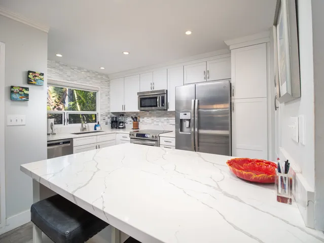 a kitchen with a sink a counter top space stainless steel appliances cabinets and a window