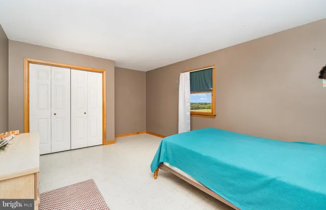 a bedroom with a bed and a window with chair