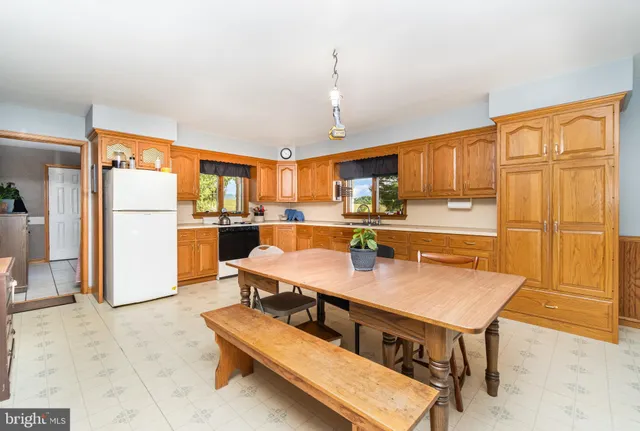 a kitchen with stainless steel appliances kitchen island granite countertop a table chairs and a refrigerator