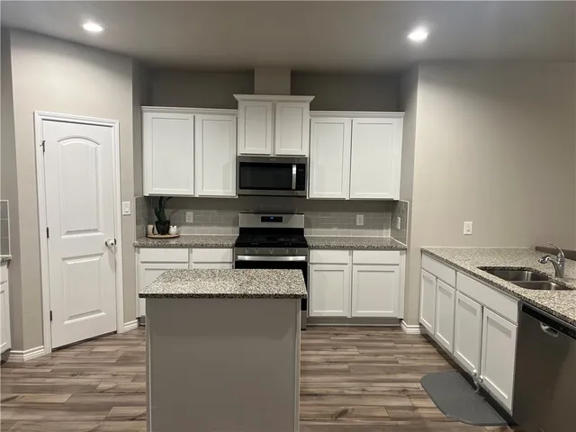 a kitchen with granite countertop a sink stove and refrigerator