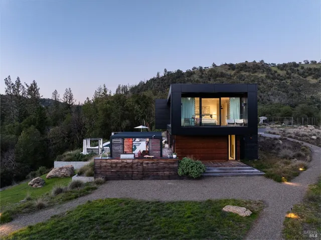 a front view of a house with a yard and mountain view in back