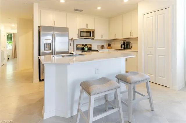 a kitchen with kitchen island white cabinets and stainless steel appliances