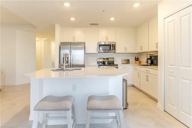 a kitchen with white cabinets and chairs
