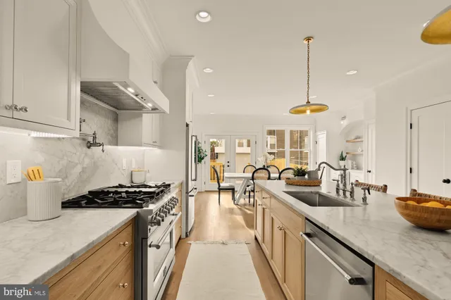 a kitchen with granite countertop a stove a sink and a white wooden cabinets