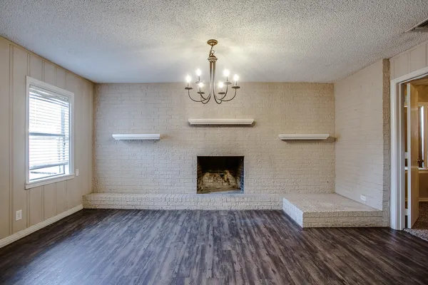 an empty room with wooden floor fireplace and windows