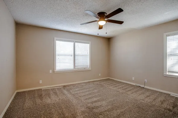 an empty room with windows and chandelier fan
