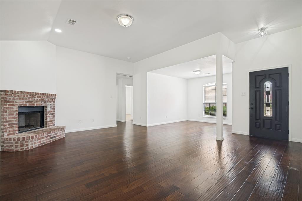 3111 Creekside Drive Sachse, TX 75048 - Photo 3 of 25 Spacious living area featuring dark wood-finish flooring, a brick fireplace with hearth, recessed lighting, and a paneled entry door with decorative glass inserts