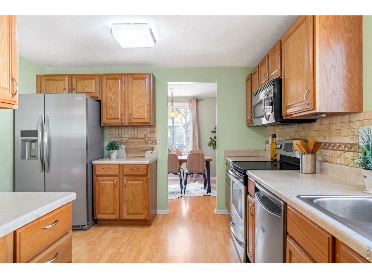 9338 Pierce Street Westminster, CO 80021 - Photo 9 of 26 a kitchen with stainless steel appliances granite countertop a refrigerator a sink dishwasher a dining table and chairs with wooden floor