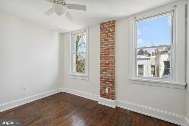 an empty room with wooden floor fan and windows