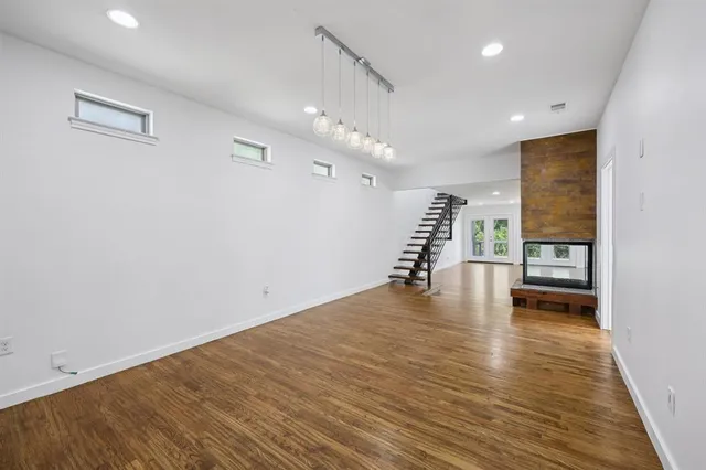 a view of empty room with wooden floor and a window