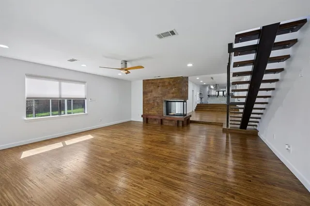 a view of a kitchen with kitchen island a sink wooden floor and a refrigerator