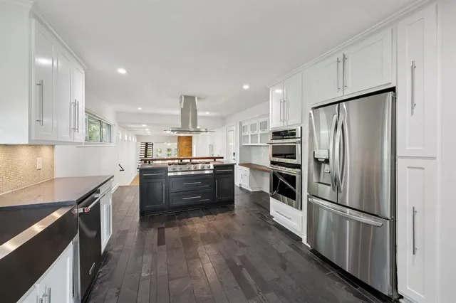 a large kitchen with cabinets wooden floor and stainless steel appliances