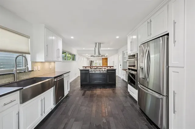 a kitchen with refrigerator a sink and wooden floor