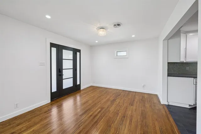 a view of an empty room with wooden floor and a window