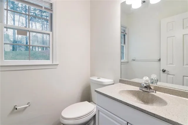 a bathroom with a granite countertop sink a toilet and a mirror