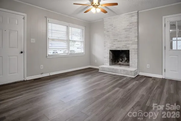 an empty room with wooden floor fireplace and window