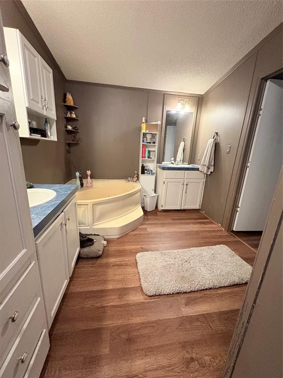 6295 Rendon New Hope Road Fort Worth, TX 76140 - Photo 23 of 38 Full bath featuring two vanities, a bath, dark wood-style floors, a textured ceiling, and crown molding