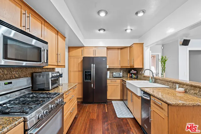 a kitchen with stainless steel appliances granite countertop a stove top oven a sink dishwasher a refrigerator and a microwave