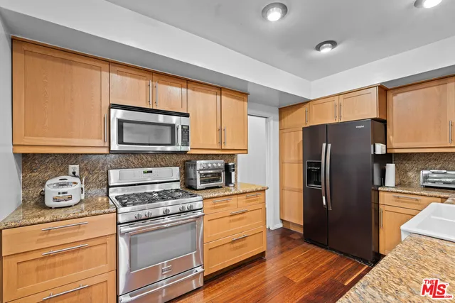 a kitchen with stainless steel appliances granite countertop a refrigerator stove and sink