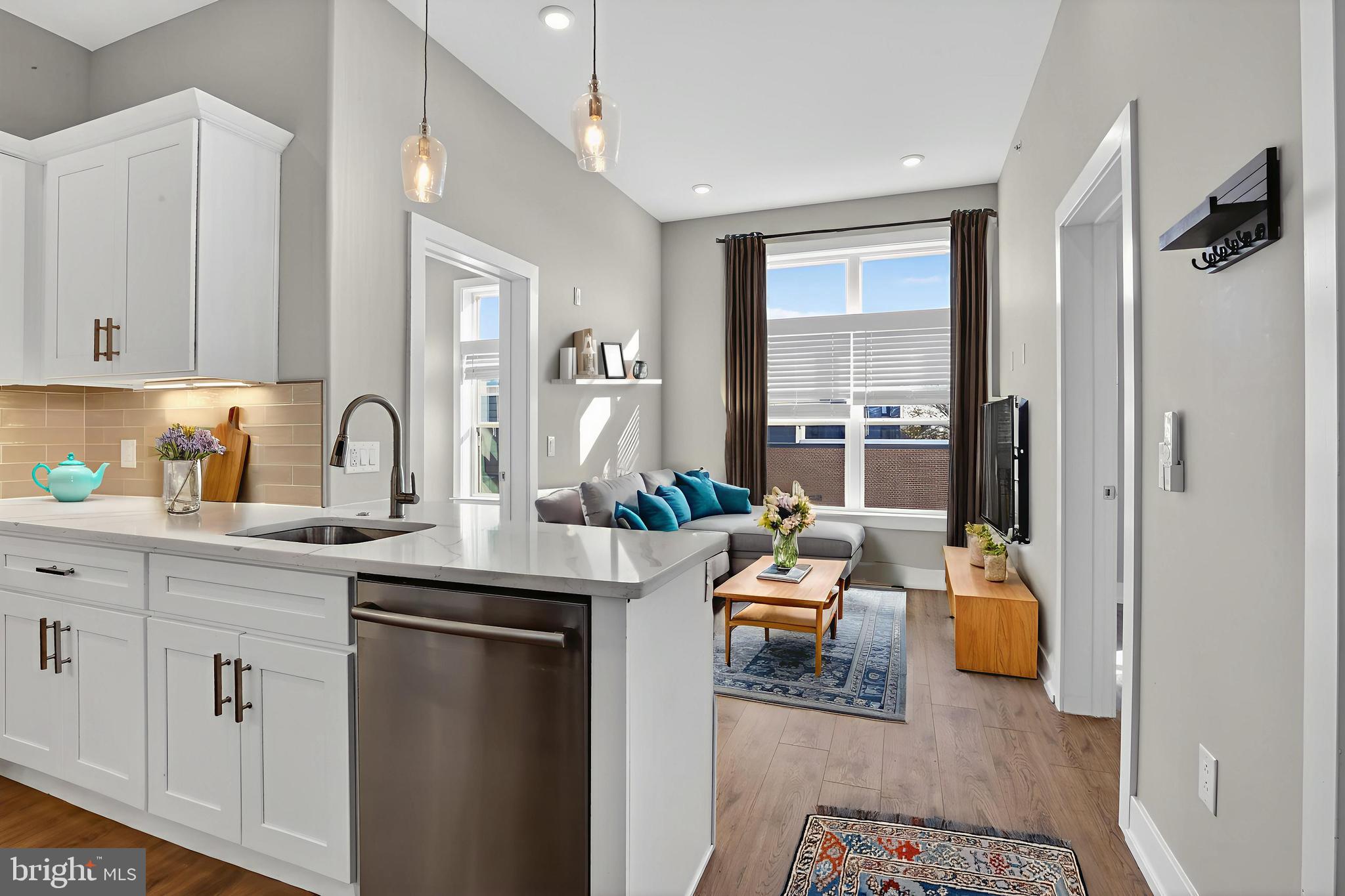 a room with stainless steel appliances granite countertop a sink and dishwasher with white cabinets
