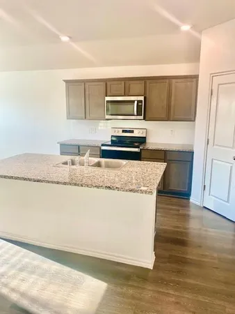 a kitchen with granite countertop a stove a sink and a microwave