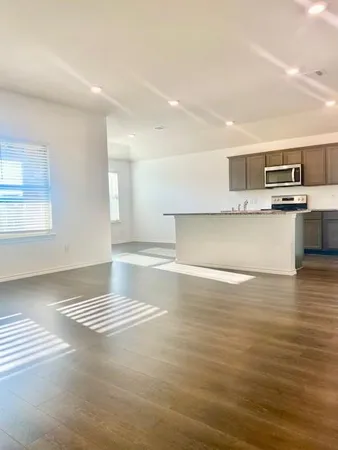 a view of kitchen and empty room with wooden floor