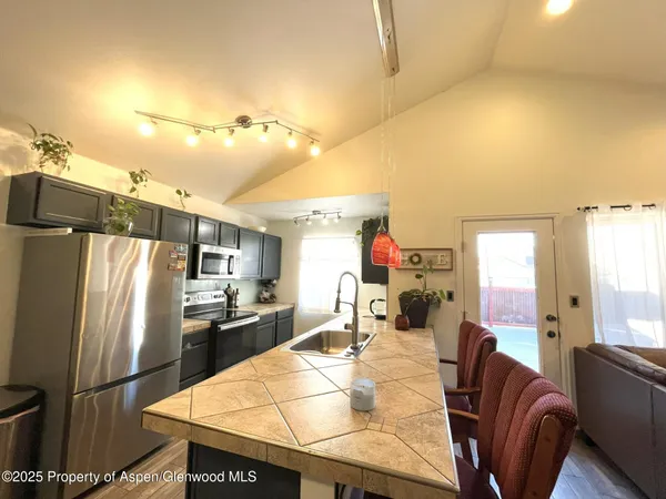 a kitchen with stainless steel appliances kitchen island granite countertop a refrigerator a stove and a sink with couches