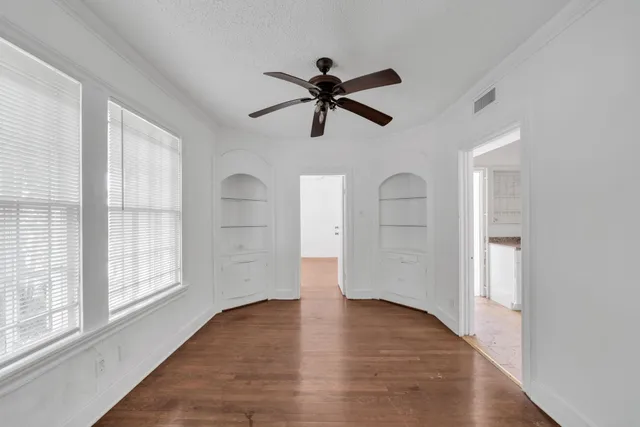 a view of empty room with wooden floor and fan