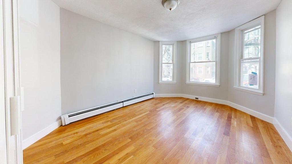 205 Chelsea Street, Unit 3 Boston, MA 02128 - Photo 20 of 33 an empty room with wooden floor and windows