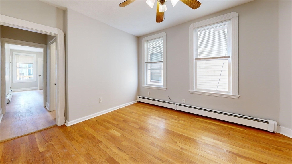 205 Chelsea Street, Unit 3 Boston, MA 02128 - Photo 22 of 33 an empty room with windows and chandelier fan