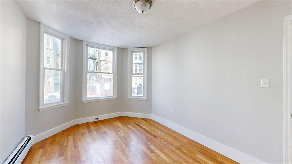 205 Chelsea Street, Unit 3 Boston, MA 02128 - Photo 3 of 33 an empty room with wooden floor and windows
