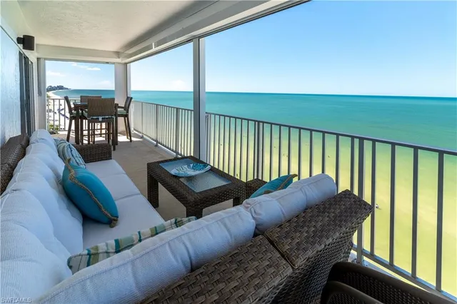 a living room with couches floor to ceiling window and wooden floor