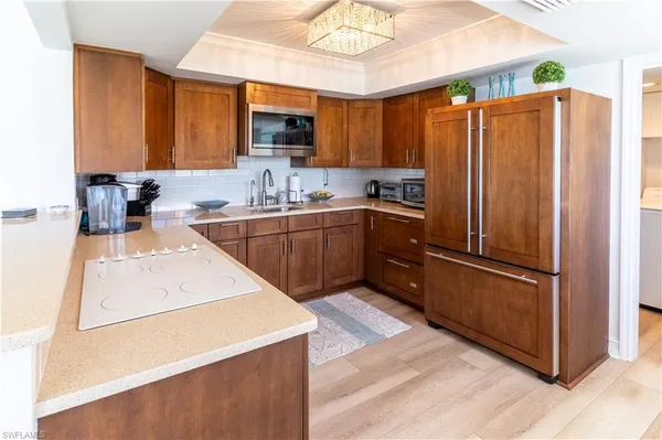 a kitchen with stainless steel appliances granite countertop a refrigerator a sink dishwasher a stove with wooden cabinets and floor