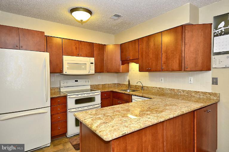 2368 Southgate Square Reston, VA 20191 - Photo 3 of 23 a kitchen with granite countertop a refrigerator a stove a sink cabinets and wooden floor