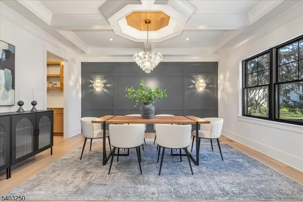 a view of a dining room and livingroom with furniture wooden floor a chandelier