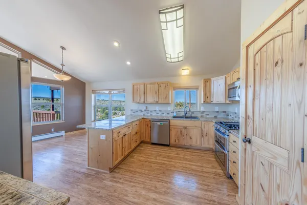 a kitchen with stainless steel appliances granite countertop hardwood floor sink stove and wooden cabinets