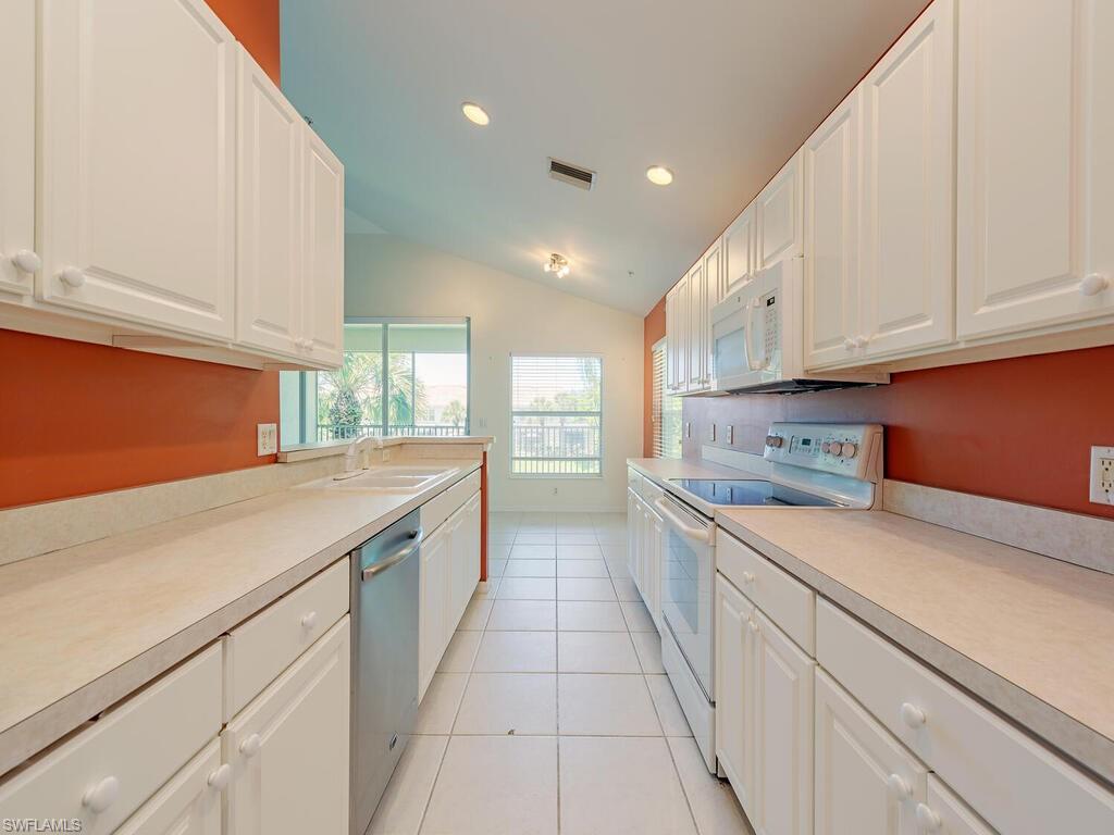 1280 Henley Street, Unit 1601 Naples, FL 34105 - Photo 4 of 15 Kitchen with white cabinets, vaulted ceiling, white appliances, and sink